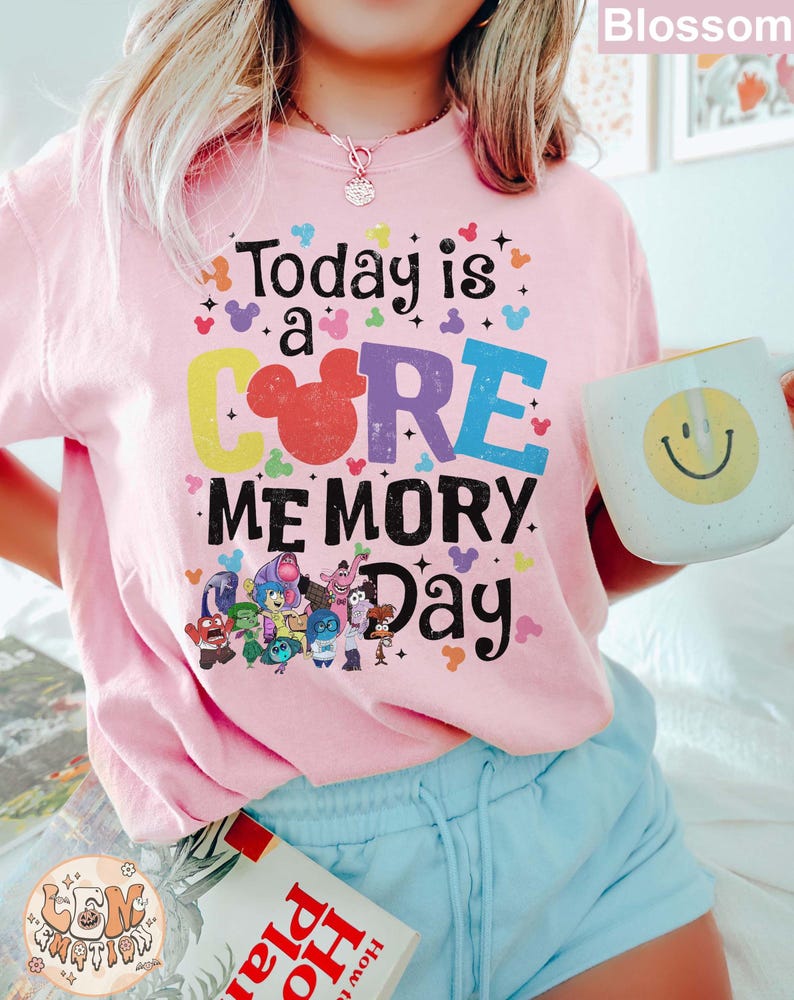 以下が含まれることがあります： ピンクのTシャツに、カラフルなグラフィックがプリントされています。「Today is a CORE MEMORY Day」という文字と、COREの文字の中にミッキーマウスの頭が描かれています。グラフィックには、映画「インサイド・ヘッド」のキャラクターも描かれています。