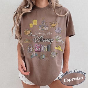 Op de afbeelding: Bruin T-shirt met de tekst "Literally just a Disney Girl" en Disney-illustraties. Het shirt is Comfort Colors Espresso van kleur en heeft een ronde hals.