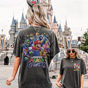 Pu&ograve; includere: T-shirt grigio scuro con una grafica colorata di Mario e altri personaggi del gioco Super Mario Galaxy. La maglietta ha anche una grafica Super Mario pi&ugrave; piccola sul davanti. Il testo "The Super Mario Galaxy" &egrave; visualizzato sul retro.