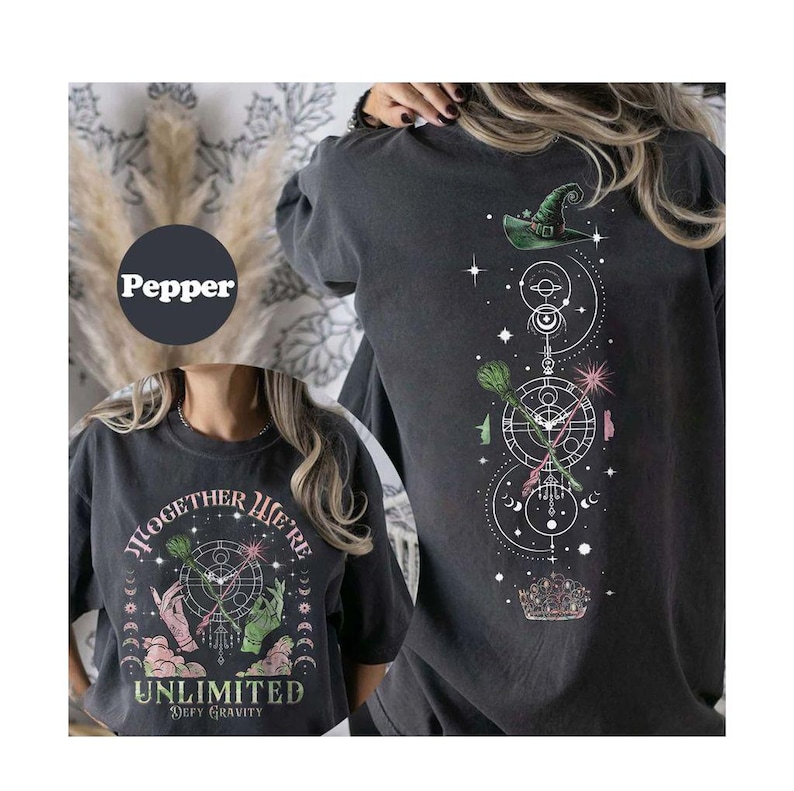 May include: Black t-shirt with a graphic print of a witch's hat, stars, and a circle with the text "Together We're Unlimited Defy Gravity".