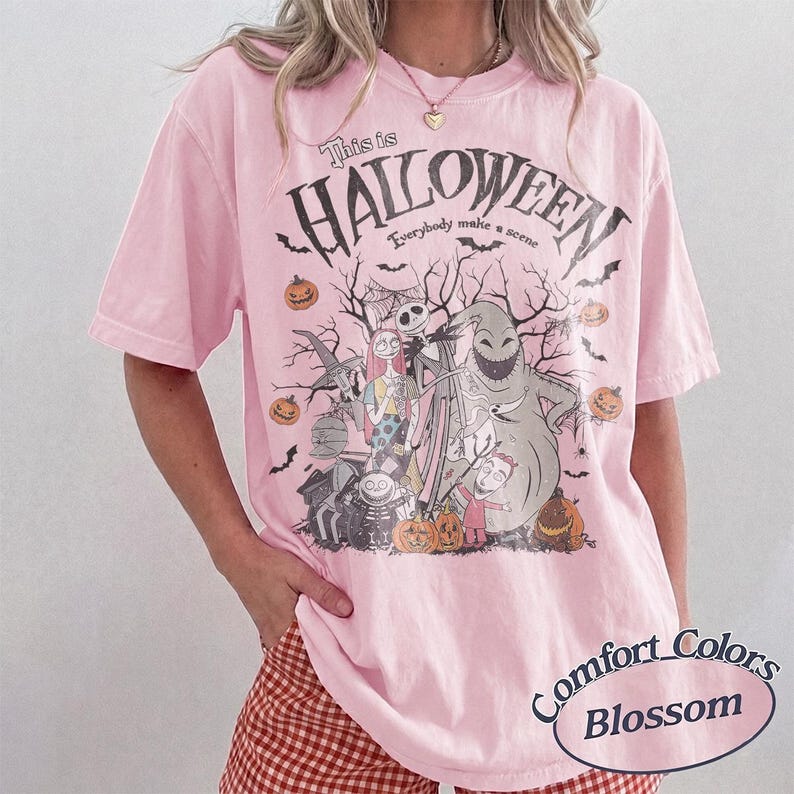 Pu&ograve; includere: T-shirt rosa chiaro con grafica di Halloween. Il design include personaggi, zucche e la scritta "This is Halloween". La maglietta &egrave; un Comfort Colors Blossom.