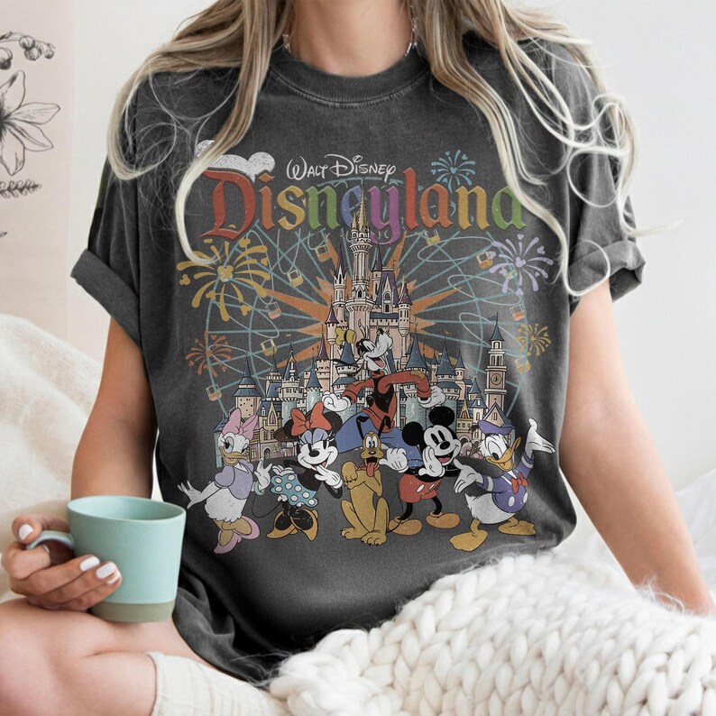 May include: A white ceramic mug with a black handle and the text "But First, Coffee" in a bold, black font. The mug is filled with a dark liquid, likely coffee, and sits on a light-colored surface.