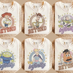 Puede incluir: Seis camisetas de color blanco roto con personajes de Toy Story. Cada camiseta muestra un personaje dentro de un círculo a cuadros con estrellas. El texto incluye 'AND BEYOND' en rojo o marrón, y 'TO INFINITY' en morado o azul según el diseño.