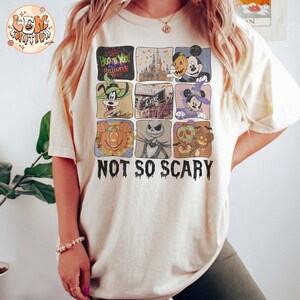 May include: A white t-shirt with a graphic of various Disney characters celebrating Halloween. The characters include Mickey Mouse, Goofy, Jack Skellington, and a pumpkin. The text "Boo to You! Halloween Spooktacular" and "Not So Scary" are printed on the shirt.