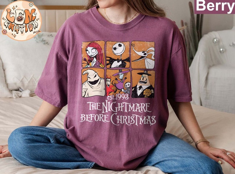 May include: A purple t-shirt with a graphic print of characters from the movie The Nightmare Before Christmas. The graphic includes Jack Skellington, Sally, Oogie Boogie, and Zero. The text "est. 1993 The Nightmare Before Christmas" is printed below the graphic.