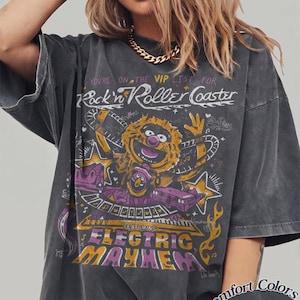 Puede incluir: Camiseta gris oscuro con un gr&aacute;fico que presenta un personaje de los Muppets y el texto "Rock'n Roller Coaster" y "Electric Mayhem". La camiseta est&aacute; etiquetada como "Comfort Colors Pepper".