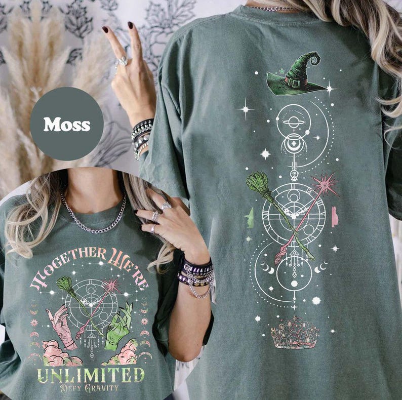 May include: A green t-shirt with a white graphic design featuring a witch's hat, a broom, a wand, and the text "Together We're Unlimited Defy Gravity".
