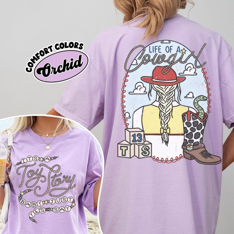 May include: A light purple t-shirt featuring a back graphic of a cowgirl with a braided ponytail, a red hat, a yellow vest, and a cow-print boot with a snake. The front graphic displays the text "It's a Toy Story baby just yes say" in rope font.