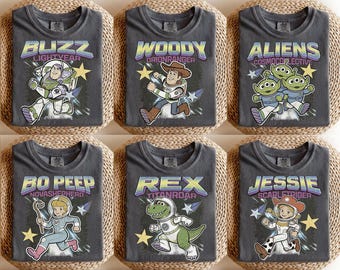 May include: Six charcoal gray t-shirts featuring characters from the animated film Toy Story. Each shirt displays a different character: Buzz Lightyear, Woody, Aliens, Bo Peep, Rex, and Jessie, with their names and associated graphics.
