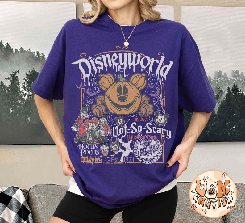 Op de afbeelding: Paars T-shirt met een afbeelding van Mickey Mouse en andere Disney-figuren. De tekst op het shirt luidt "Disneyworld Mickey's Not-So-Scary Halloween Party, Est. 1971".
