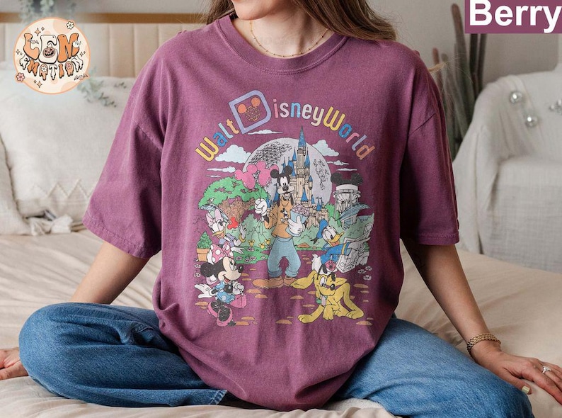 May include: A purple t-shirt with a vintage-style graphic of Mickey Mouse and friends at Walt Disney World. The graphic features the text "Walt Disney World" in a colorful, retro font.