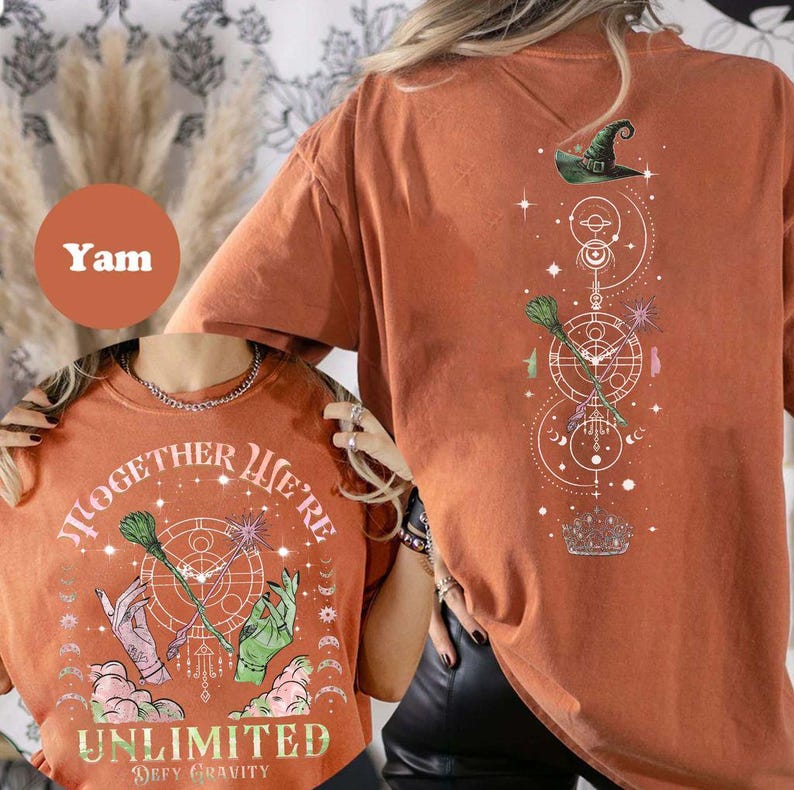 May include: Orange t-shirt with a graphic of a witch's hat, broomsticks, and stars. The text on the shirt says "Together We're Unlimited - Defy Gravity".