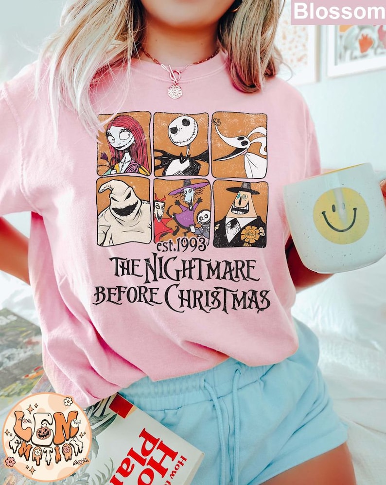 May include: A pink t-shirt with a vintage-style graphic of characters from the movie "The Nightmare Before Christmas". The graphic features Jack Skellington, Sally, Zero, Oogie Boogie, and other characters in a grid pattern. The text "est. 1993" and "The Nightmare Before Christmas" is printed below the graphic.