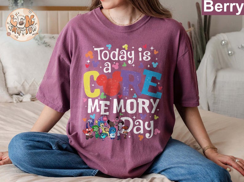 以下が含まれることがあります： 「Today is a CORE MEMORY Day」という文字と、漫画のミッキーマウスの頭が描かれた紫色のTシャツ。Tシャツには、映画「インサイド・ヘッド」の漫画のキャラクターのグループも描かれている。