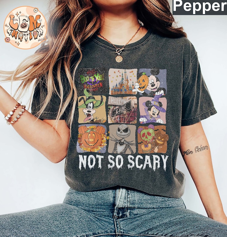 May include: A dark gray t-shirt with a vintage-style graphic featuring various Disney characters and Halloween imagery. The graphic includes Mickey Mouse, Goofy, Jack Skellington, and a pumpkin. The text "Boo to You Halloween" and "Not So Scary" are also included in the graphic.