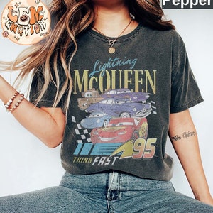 May include: A black t-shirt with a vintage-style graphic of Lightning McQueen from the Cars movie. The graphic features McQueen's number 95 and the text "Lightning McQueen" and "Think Fast".
