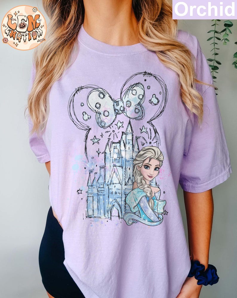Puede incluir: Una camiseta morada con un boceto de un castillo, un lazo y una princesa con cabello rubio. La princesa lleva un vestido azul y una corona. El texto "Orchid" es visible en la esquina superior derecha de la imagen.