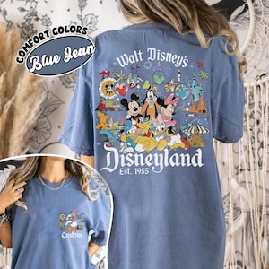 Puede incluir: Camiseta azul vaquero con un gr&aacute;fico de Disneyland en la espalda, con Mickey Mouse, Minnie Mouse y otros personajes de Disney. La parte delantera tiene un gr&aacute;fico m&aacute;s peque&ntilde;o con Daisy Duck y la palabra "Custom". La camiseta tambi&eacute;n tiene las palabras "Comfort Colors" y "Blue Jean".