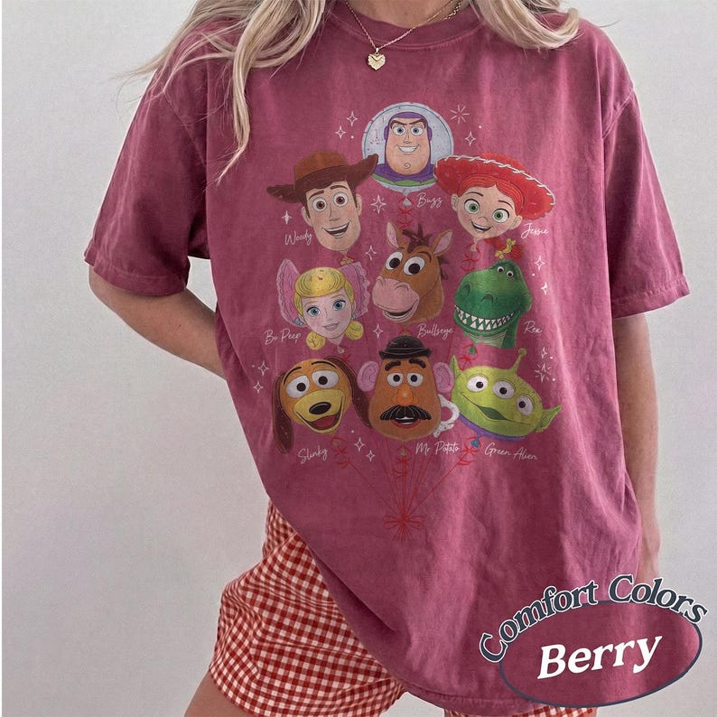 以下が含まれることがあります： ベリー色の半袖Tシャツで、風船の束のように配置されたトイ・ストーリーのキャラクターのグラフィックプリントが施されています。デザインには、ウッディ、バズ・ライトイヤー、ジェシー、ボー・ピープ、ブルズアイ、レックス、スリンキー・ドッグ、ミスター・ポテトヘッド、エイリアンが含まれています。