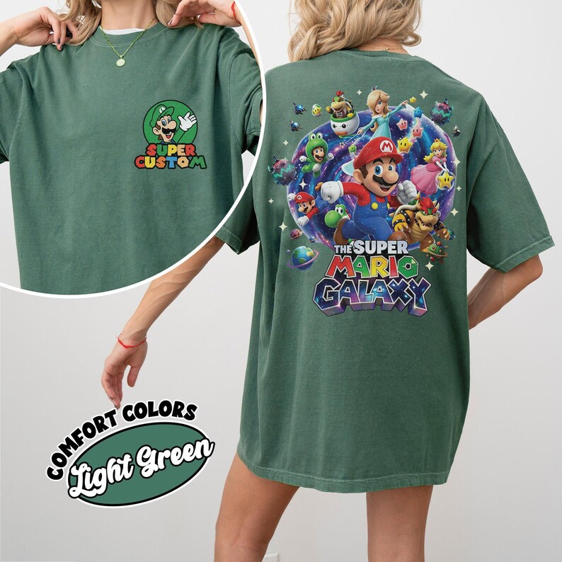 Pu&ograve; includere: T-shirt verde chiaro con grafica Super Mario Galaxy sul retro e logo Super Custom sul davanti. La grafica presenta Mario, Luigi, la Principessa Peach e altri personaggi. La maglietta &egrave; etichettata "Comfort Colors" e "Light Green".