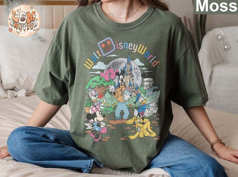May include: A green t-shirt with a vintage-style graphic of Mickey Mouse and friends at Walt Disney World. The text "Walt Disney World" is printed in a colorful arc above the characters.