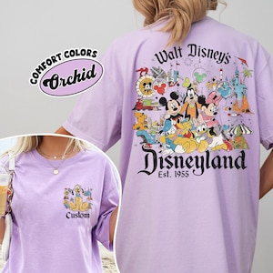 Puede incluir: Camiseta de color lila claro con un gr&aacute;fico de Disneyland en la espalda con Mickey Mouse, Minnie Mouse y otros personajes de Disney. El bolsillo delantero tiene un gr&aacute;fico de Pluto. La camiseta tiene el texto "Comfort Colors Orchid" y "Custom".