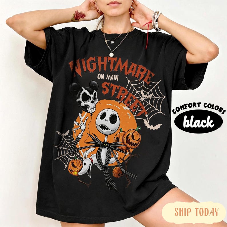 Pu&ograve; includere: Una t-shirt nera con una stampa grafica che riporta il testo Nightmare on Main Street. Il design include un personaggio scheletro, un cane fantasma, zucche, ragnatele e pipistrelli nei colori arancione, bianco e nero. La maglia ha maniche corte.