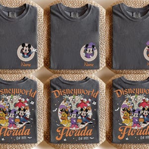 May include: Dark gray t-shirts featuring Disney characters in Halloween costumes. The shirts have a round neck and short sleeves. Some shirts have a Mickey Mouse graphic with the name "Name" below. Other shirts have a "Disneyworld Florida" graphic.
