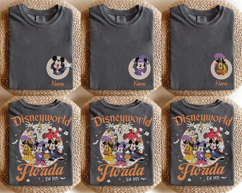 May include: Dark gray t-shirts featuring Disney characters in Halloween costumes. The shirts have a round neck and short sleeves. Some shirts have a Mickey Mouse graphic with the name "Name" below. Other shirts have a "Disneyworld Florida" graphic.