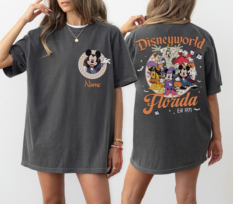 May include: Dark gray t-shirt featuring a Mickey Mouse design on the front and a Disney World Florida graphic on the back. The front design includes a circular Mickey Mouse graphic with the word "Name" below. The back graphic features Disney characters.