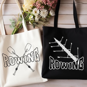Puede incluir: Dos bolsas de tela con la palabra "ROWING" impresa en ellas. Una bolsa es blanca con texto negro y un par de remos cruzados. La otra bolsa es negra con texto blanco y una imagen estilizada de un bote de remo.