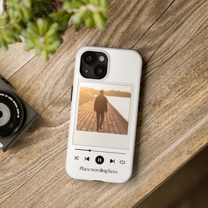 May include: White phone case featuring a photograph of a person walking away from the camera on a path beside a body of water. The image is presented in a Polaroid frame with a music player interface beneath it. The text "Place wording here" is displayed below the music player interface.