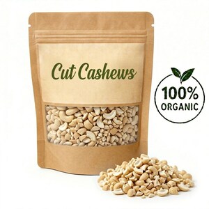 May include: A brown paper bag with a clear window displaying cut cashews. The text "Cut Cashews" is printed on the front. A circular logo with the words "100% ORGANIC" is on the right. A small pile of cashews is in front of the bag.