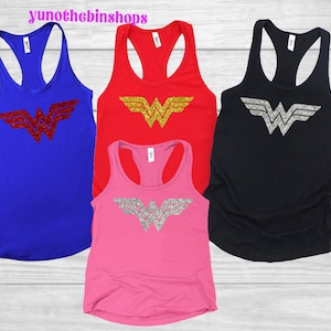May include: Four racerback tank tops in blue, red, pink, and black. Each tank top features a glittery "W" logo. The blue tank top has a red logo, the red tank top has a gold logo, the pink tank top has a silver logo, and the black tank top has a silver logo.