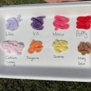 May include: A white styrofoam tray with eight different colors of pipe cleaners. The colors are lilac, iris, hibiscus, poppy, cotton candy, tangerine, sunshine, and teddy bear.