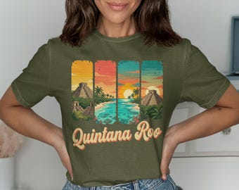 May include: Olive green t-shirt featuring a colorful graphic of Mayan pyramids, a beach, and a sunset. The text "Quintana Roo" is printed in a vintage style. The shirt is made of a soft material.