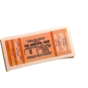 May include: A vintage concert ticket for The Grateful Dead at Barton Hall, Ithaca, New York, on May 8, 1977. The ticket is orange and white, with the band's name and concert details printed on it. The ticket also includes the price and seat information.