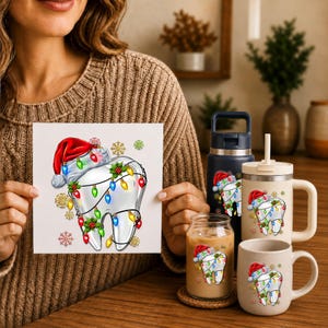 May include: A white tooth graphic wearing a red Santa hat and wrapped in colorful Christmas lights with holly leaves and snowflakes. This design appears on a square card, a dark blue water bottle, a beige tumbler with a straw, and a beige mug.