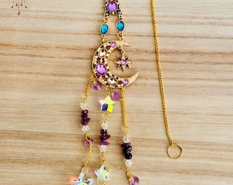 May include: Gold chain with a crescent moon charm adorned with purple and white crystals, a star charm, and dangling amethyst and crystal beads.