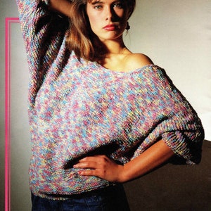 May include: A woman wearing a multi-colored knit sweater with a black beret and blue jeans.