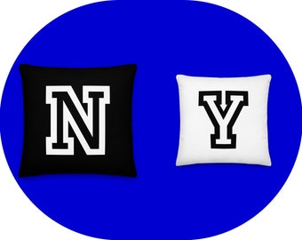 May include: Two decorative throw pillows with the letters "N" and "Y" in a black and white varsity style font. The "N" pillow is black with white lettering and the "Y" pillow is white with black lettering.