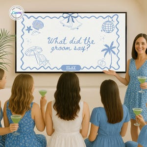 May include: A group of women gather around a screen displaying a wedding-themed game with the text "What did the groom say?". The screen features beach-themed illustrations. The women are dressed in blue and white dresses and holding green cocktails.