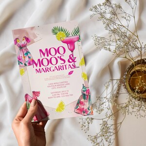 May include: A pink invitation with the text "MOO MOO'S & MARGARITAS" features illustrations of a margarita, dresses, and lemons. The invitation includes event details and is held by a hand.