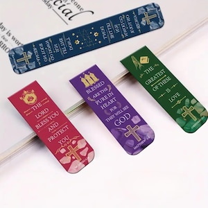 May include: A collection of colorful bookmarks with religious quotes and cross designs. The bookmarks are in shades of blue, red, purple, and green. Each bookmark features a different quote and a cross graphic. The text includes phrases like "The Lord Bless You" and "The Greatest of These is Love."