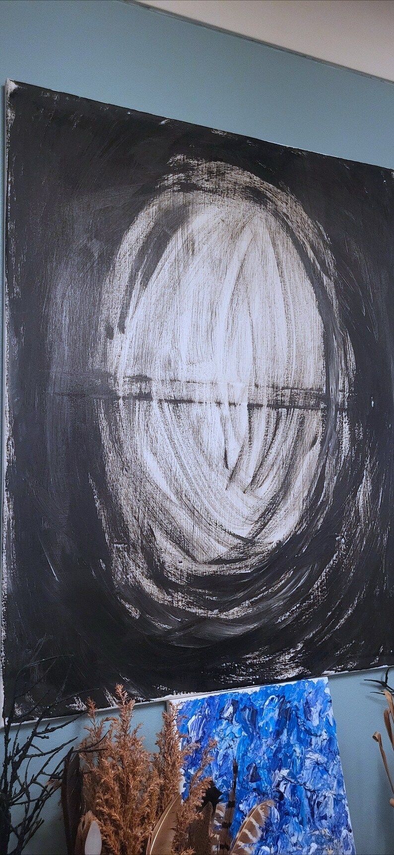 Op de afbeelding: Abstract schilderij met een grote witte cirkel in het midden, omringd door zwarte verf. De cirkel is gemaakt van veel witte penseelstreken. Het schilderij is op canvas en is ingelijst.