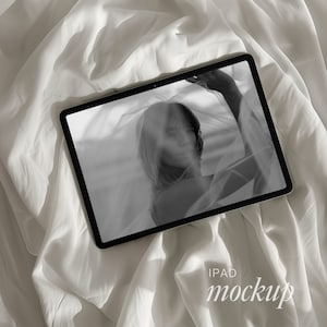 Puede incluir: Una foto en blanco y negro de una persona con una tela transparente drapeada sobre su cabeza y hombros, mostrada en una tableta iPad blanca. El texto "IPAD mockup" es visible debajo de la tableta.