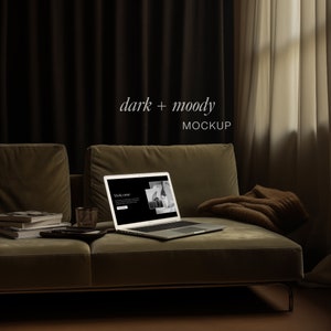 Op de afbeelding: Een laptop met een website die openstaat op het scherm staat op een groene bank. De bank staat in een kamer met donkere gordijnen en een raam met witte gordijnen. De tekst "dark + moody MOCKUP" staat boven de bank.
