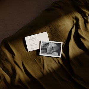 May include: Two business cards with the name Olivia and the word Photographer. The top card has contact information and the bottom card has a black and white photo of a woman.