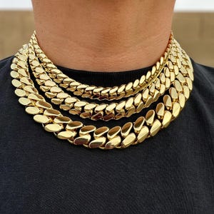 Three Miami Cuban link chains in varying thicknesses hanging closely around the neck, showcasing different sizes with tight, interlocking links and a polished finish.