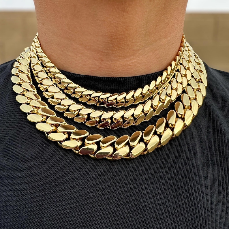 Three Miami Cuban link chains in varying thicknesses hanging closely around the neck, showcasing different sizes with tight, interlocking links and a polished finish.
